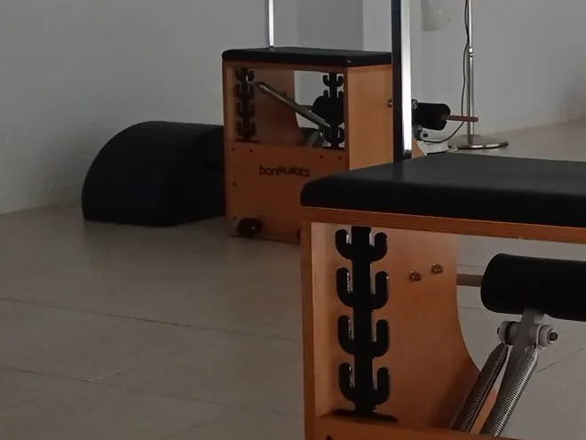 El barril negro apoyado en el suelo, junto a una silla de pilates de madera